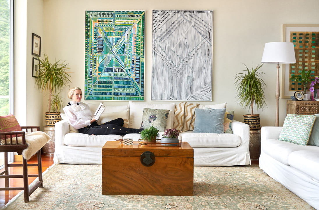 Artist and interior designer Greer Howland Smith lounges at her Southside home wearing an Edward Achour frill blouse and wide-leg pants.