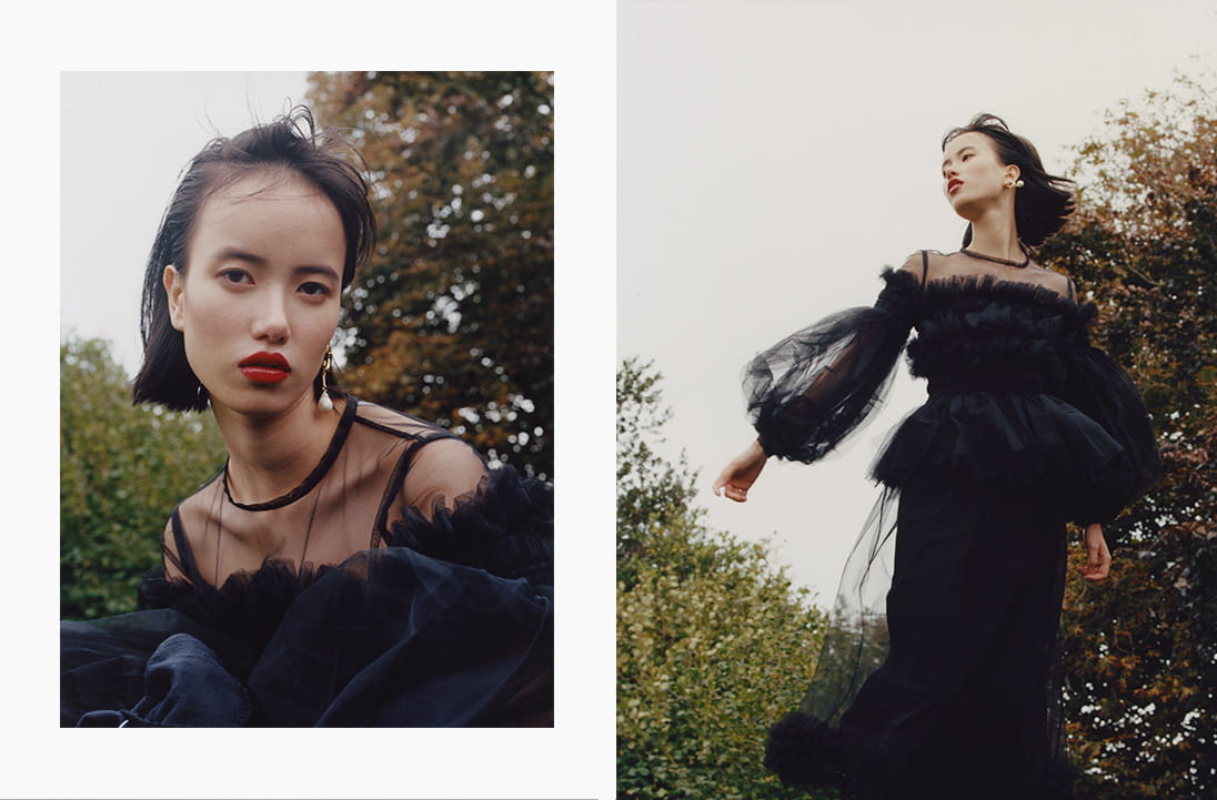 A model poses in the garden in a black tulle look by Molly Goddard