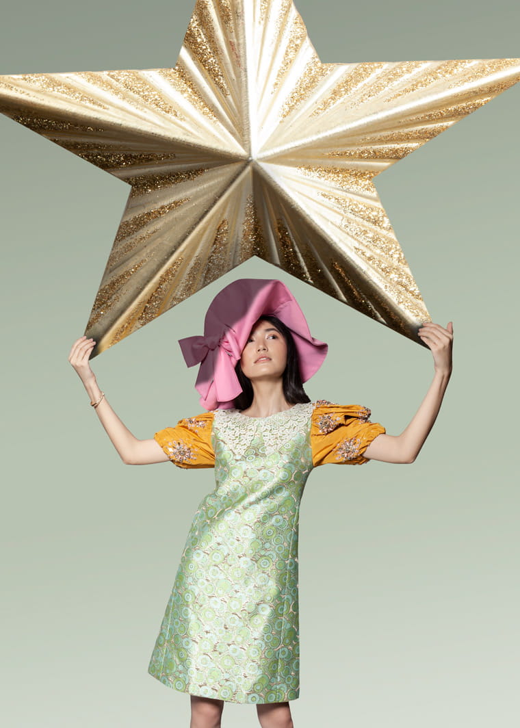 A model plays with a life-sized star ornament wearing Miu Miu