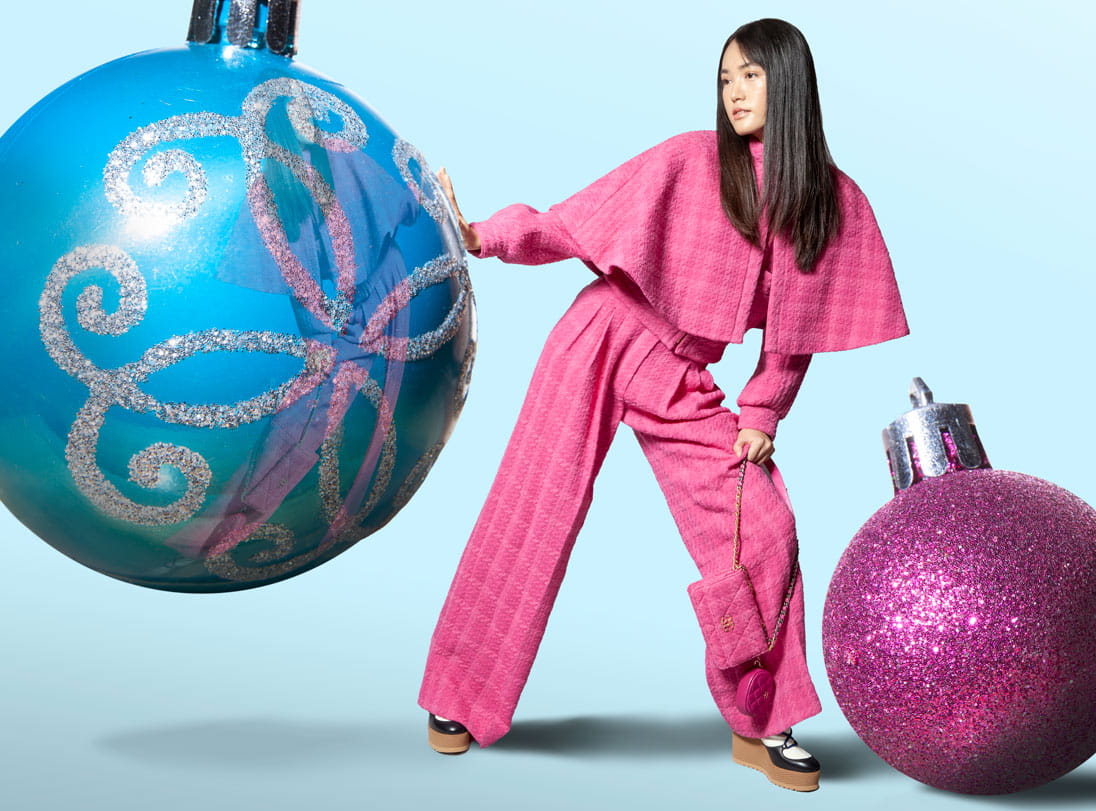 A model plays with life-sized Christmas ornaments wearing Chanel