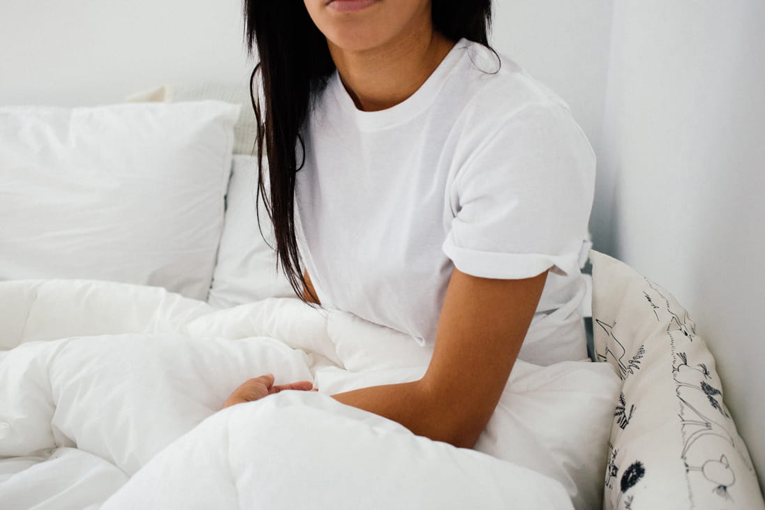 A woman with white shirt is sitting on the sofa