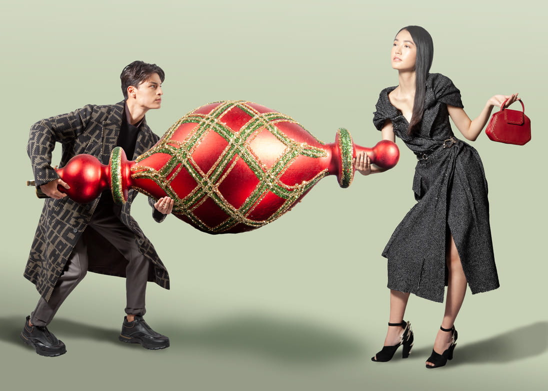 Models carry a life-sized Christmas ornament