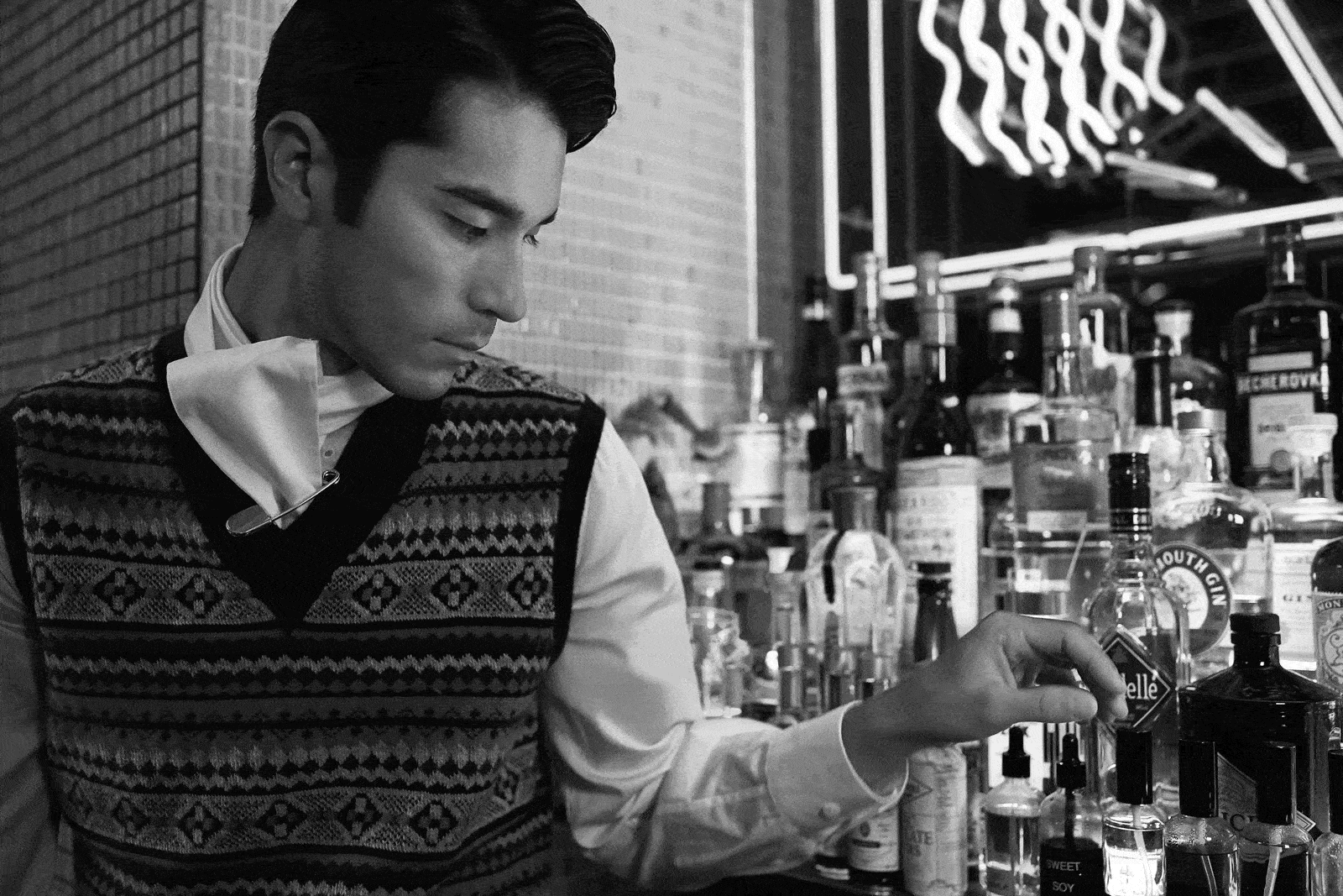 A model wearing Burberry reaches for a bottle of liquor in a neon-lit bar