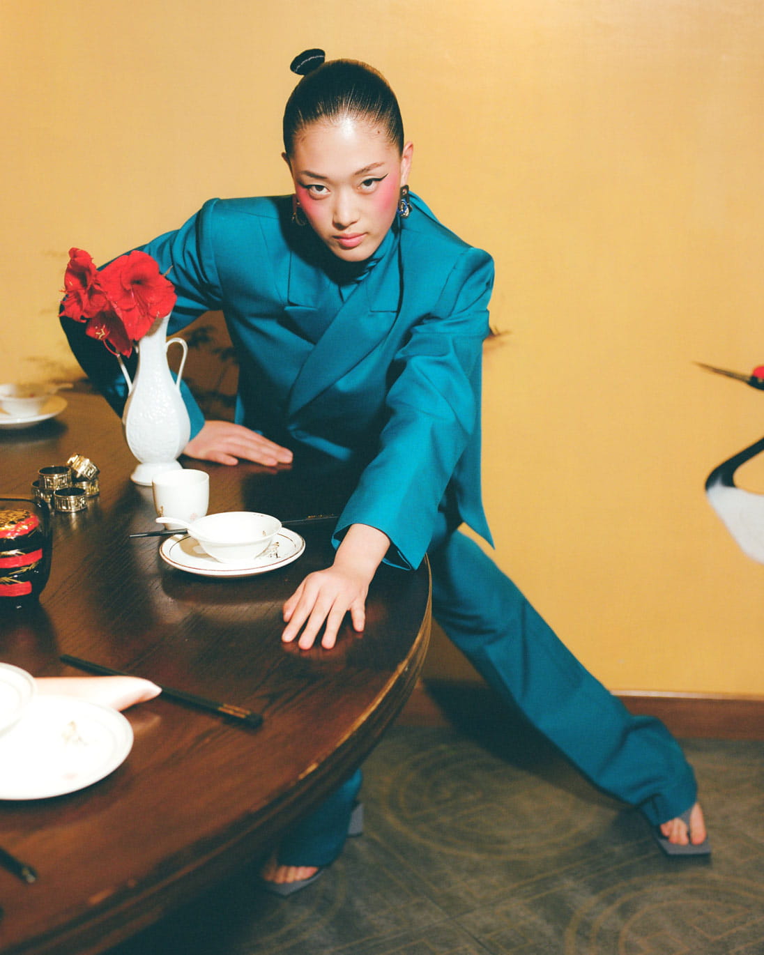 A model sits at a dining table in a Balenciaga suit