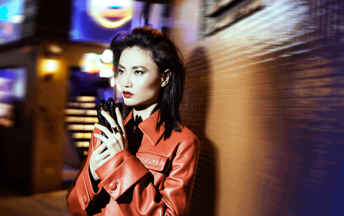 A model poses in leather looks by Versace and Hermès in Hong Kong’s neon-lit night 