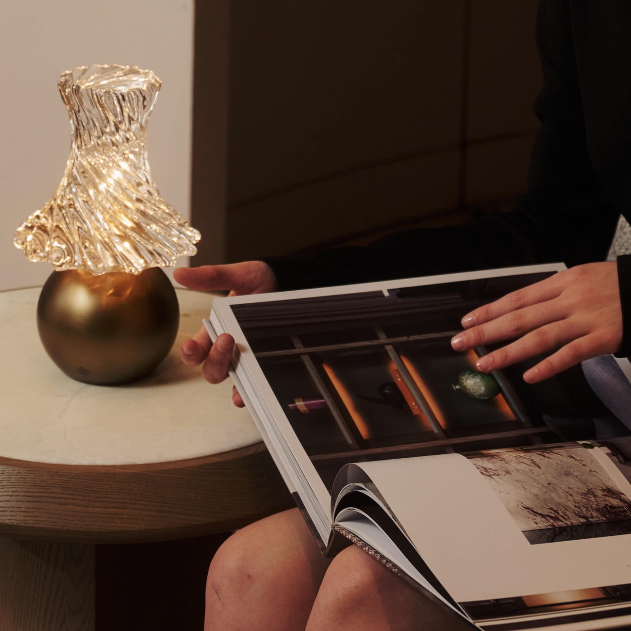 A woman reading with an Andre Fu lamp