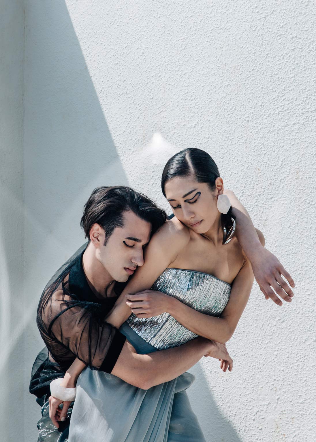 A female model strikes a pose in a silver Emporio Armani gown while being embraced