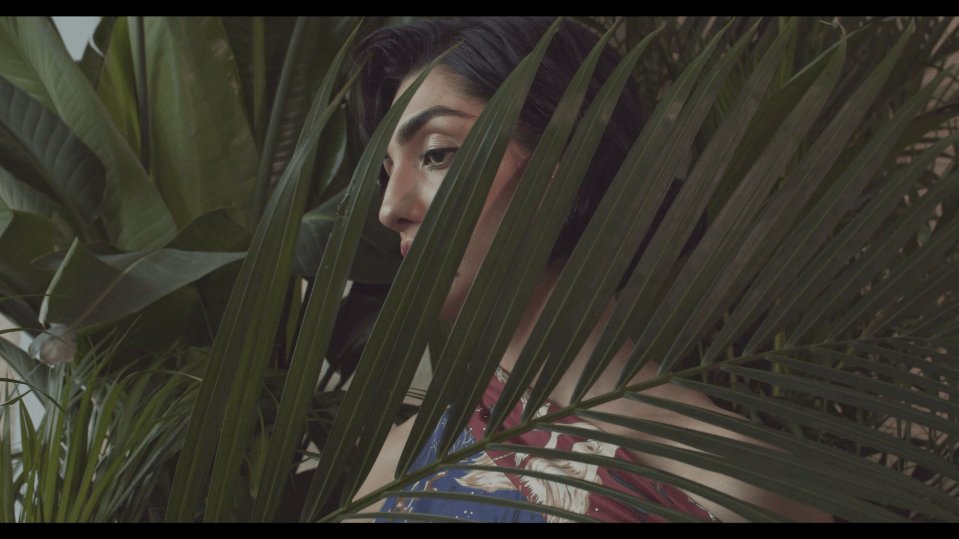 A model is partly obscured by a tropical plant